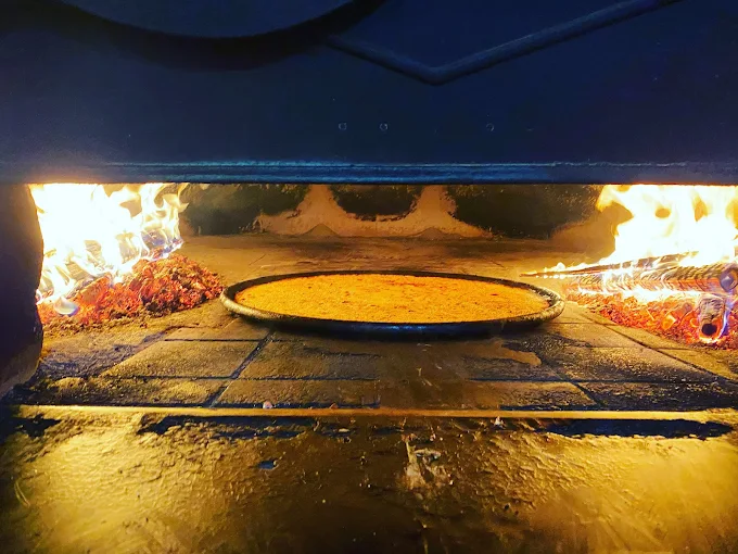 Socca en cuisson au feu de bois dans le four traditionnel